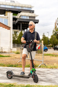 Commuter hipster man is using electric scooter on the outskirts of a city. eco transport concept