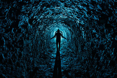 Rear view of silhouette man standing in tunnel