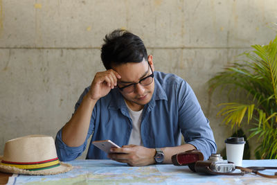 Full length of man using mobile phone while sitting on table