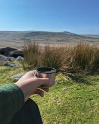 Midsection of man holding umbrella on field