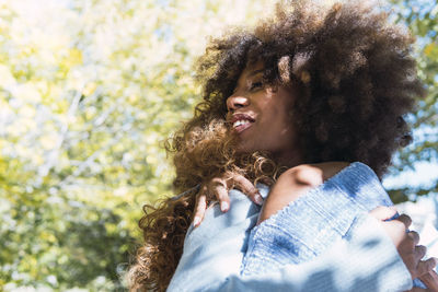 Two female afro american friends and happy best friends hugging each other and laughing in the park.