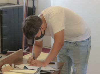 Young man signing book on table