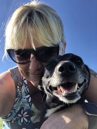 Portrait of woman with dog against sky