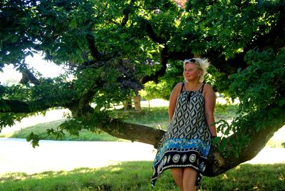 Thoughtful mature woman standing against tree at park