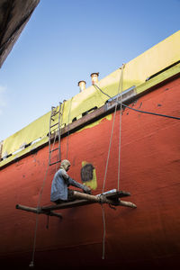 Low angle view of man working against clear sky