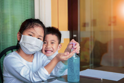 Portrait of smiling kids using hand sanitizer