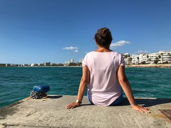 Rear view of man looking at sea against sky