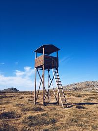 Lifeguard hut on field against clear blue sky