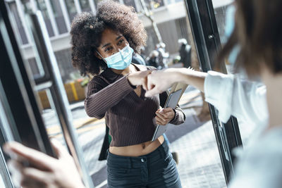 Businesswoman giving fist bump to colleague at doorway