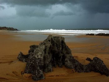 Scenic view of beach against cloudy sky