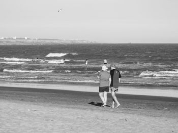 Rear view of woman on beach against sky