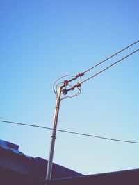 Low angle view of power lines against clear blue sky