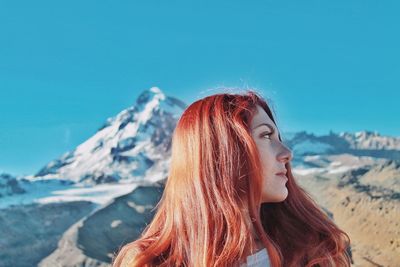 Young woman looking away against mountains in winter