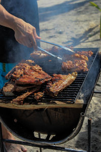 Cropped image of man preparing food over barbecue grill