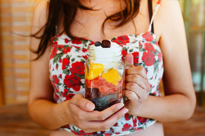 Unrecognizable woman holding and showing a jar with chopped fruit salad. mango, apple, grapes