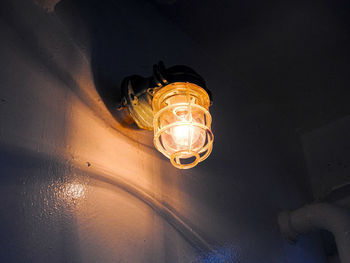 Low angle view of illuminated light bulb hanging from ceiling