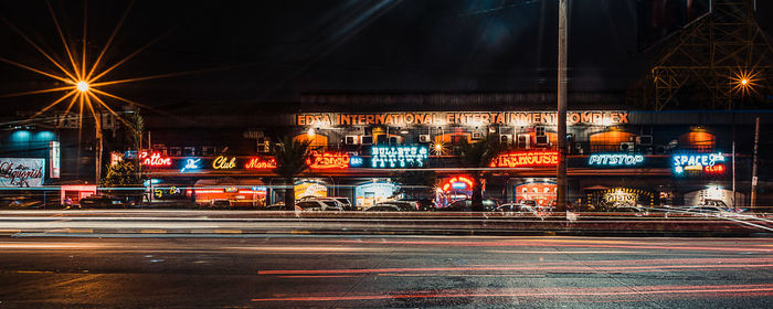 Light trails on street against illuminated buildings in city at night