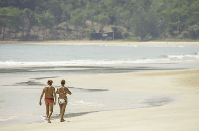 Rear view of people walking on beach