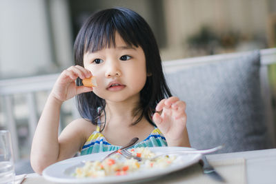 Girl holding food while looking away