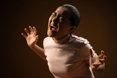 Mid adult woman standing against black background