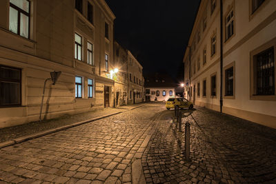 Illuminated street amidst buildings at night