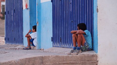 Full length of men sitting on wall