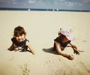 Siblings buried in sand at beach