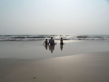 Men on beach against clear sky