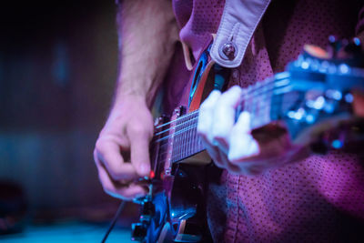 Midsection of man playing guitar