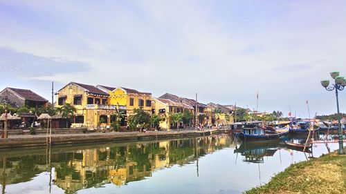Boats moored by houses against sky