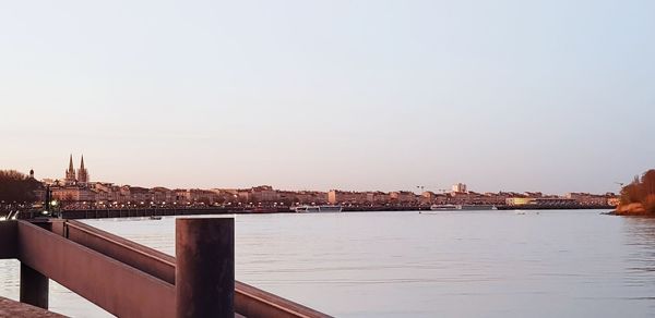 View of bridge over river by buildings against clear sky