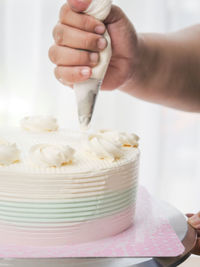Midsection of person preparing cake