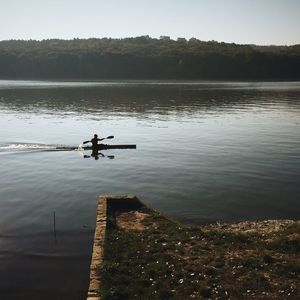 Silhouette man standing on lake against sky