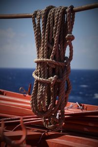 Close-up of rope tied to moored on sea against sky