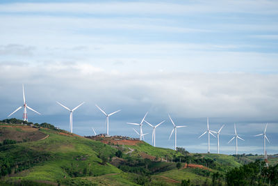 Wind turbines on field against sky