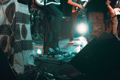 Low section of musicians playing guitars on stage during music concert