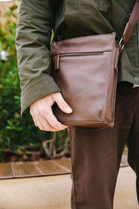 Midsection of man standing with bag