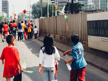 Rear view of people walking on road