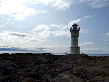 Lighthouse by sea against sky