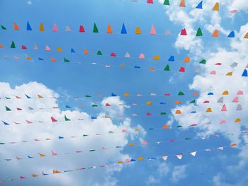 Low angle view of multi colored flags against blue sky