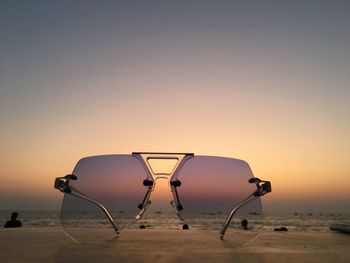Silhouette parasols on beach against clear sky during sunset