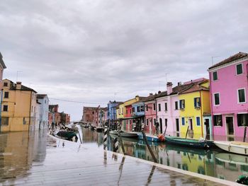 Houses by canal against sky in city