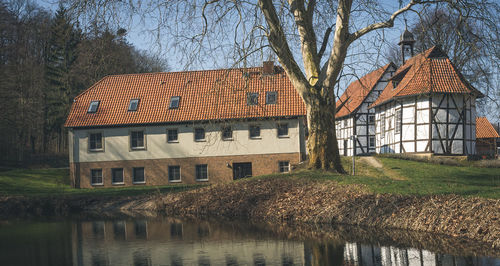 Bare tree and house against sky