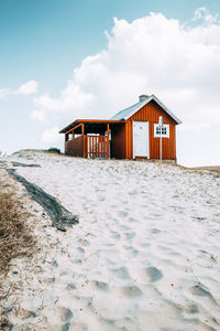 House on beach by building against sky