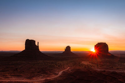 Silhouette rock formations on landscape against sky during sunset in monument valley