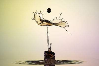 Close-up of drop falling on pole against white background