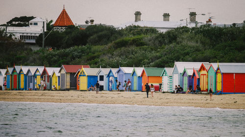 People by beach huts on shore