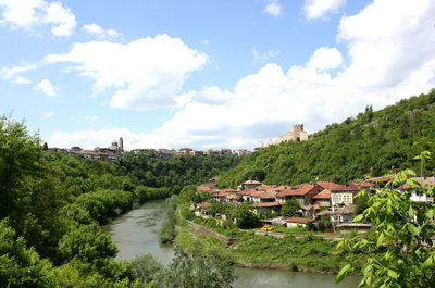 Panoramic view of trees, river and buildings against sky