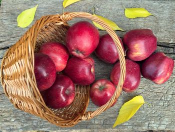 High angle view of apples with basket on wooden table