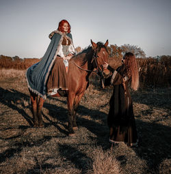 Man riding horses on field against sky